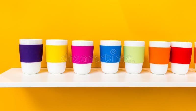 Fila de la taza de cerámica blanca con la taza colorida del silicón del pantone imágenes de archivo libres de regalías Fila de la taza de cerámica blanca con la taza colorida del silicón del pantone imágenes de archivo libres de regalías