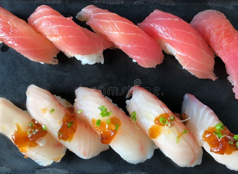 File dei sushi freschi Makuro di Akami Nigiri del giapponese e dei sushi dalla coda gialla di Hamachi Nigiri sul servizio nero de immagini stock File dei sushi freschi Makuro di Akami Nigiri del giapponese e dei sushi dalla coda gialla di Hamachi Nigiri sul servizio nero de immagini stock