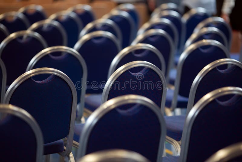 File delle sedie vuote del metallo in una grande sala di montaggio Sedie vuote nella sala per conferenze Sala riunioni interna Vi immagine stock libera da diritti File delle sedie vuote del metallo in una grande sala di montaggio Sedie vuote nella sala per conferenze Sala riunioni interna Vi immagine stock libera da diritti