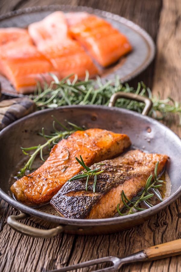 Salmon fillets. Grilled salmon, sesame seeds herb decorationon on vintage pan or black slate board. fish roasted on an old wooden table.Studio shot. Salmon fillets. Grilled salmon, sesame seeds herb decorationon on vintage pan or black slate board. fish roasted on an old wooden table.Studio shot.