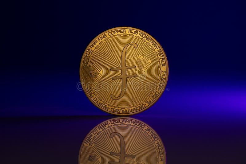 Filecoin FIL Physical Coin Placed On reflective surface and lit with blue light from the side. Filecoin FIL Physical Coin Placed On reflective surface and lit with blue light from the side