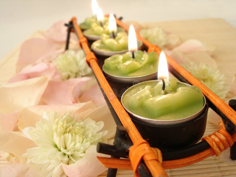 Fileira de velas verdes sobre a palha matt com pétalas cor-de-rosa foto de stock Fileira de velas verdes sobre a palha matt com pétalas cor-de-rosa foto de stock