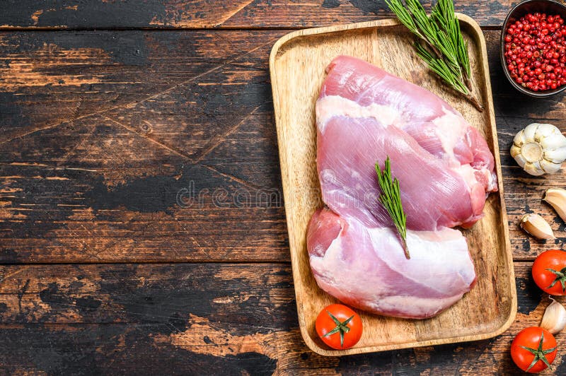 Raw fillet of farm Turkey thigh. Dark wooden background. Top view. Copy space. Raw fillet of farm Turkey thigh. Dark wooden background. Top view. Copy space.