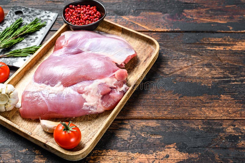 Raw fillet of farm Turkey thigh. Dark wooden background. Top view. Copy space. Raw fillet of farm Turkey thigh. Dark wooden background. Top view. Copy space