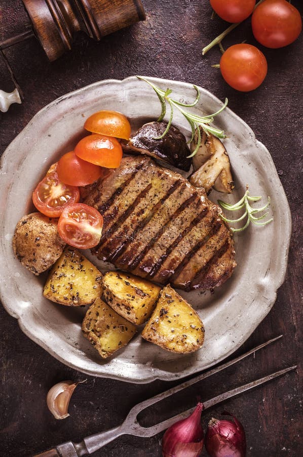 Filete asado a la parrilla con la patata cortada y los tomates verticales fotos de archivo Filete asado a la parrilla con la patata cortada y los tomates verticales fotos de archivo
