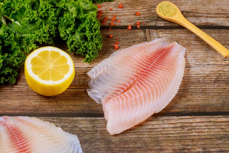Filete crudo de tilapia sobre mesa con limón y especias imágenes de archivo libres de regalías