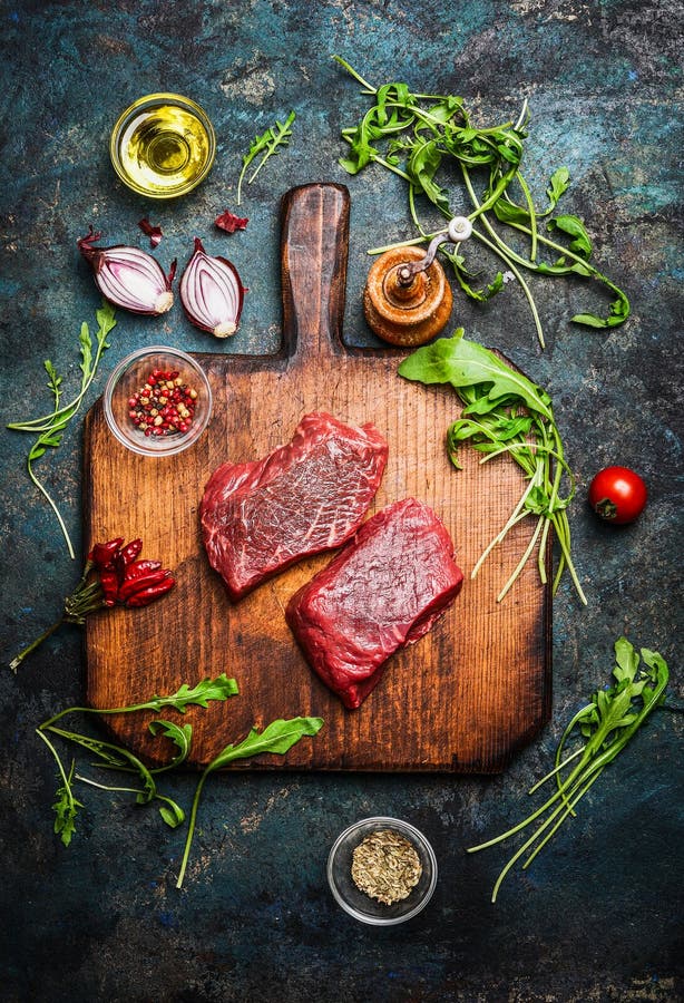 Filete de carne de vaca delicioso en tabla de cortar del vintage con los diversos ingredientes frescos para cocinar sabroso en fo fotos de archivo libres de regalías Filete de carne de vaca delicioso en tabla de cortar del vintage con los diversos ingredientes frescos para cocinar sabroso en fo fotos de archivo libres de regalías