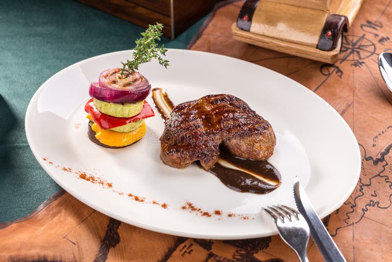Filete de carne de vaca asado a la parrilla con las verduras asadas a la parrilla en la placa blanca en viejo fondo del mapa imagen de archivo libre de regalías Filete de carne de vaca asado a la parrilla con las verduras asadas a la parrilla en la placa blanca en viejo fondo del mapa imagen de archivo libre de regalías