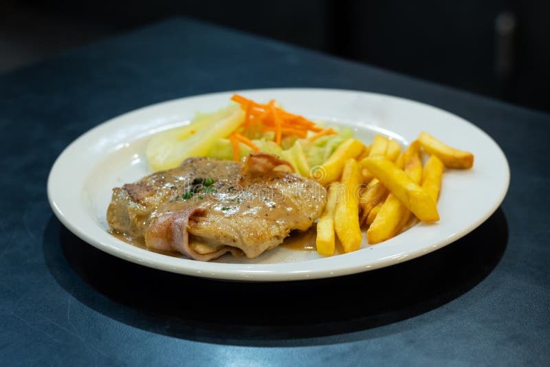 Filete del pollo con las patatas fritas y la ensalada en la placa blanca