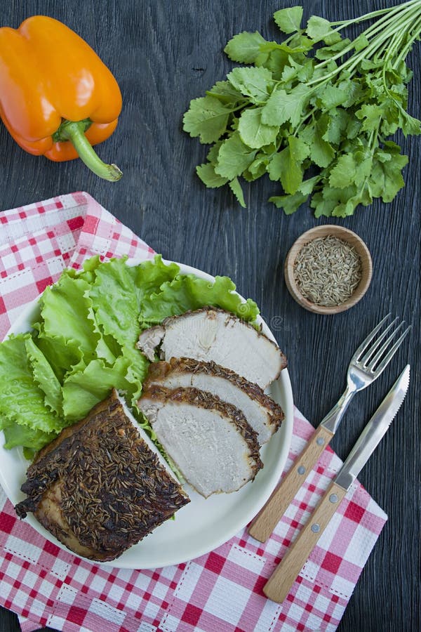 Filetto di carne di maiale al forno in spezie affettate su un piatto bianco con insalata verde Priorit? bassa di legno scura fotografie stock Filetto di carne di maiale al forno in spezie affettate su un piatto bianco con insalata verde Priorit? bassa di legno scura fotografie stock