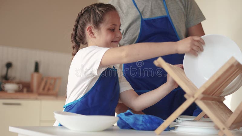 Filha e pai lavando pratos. família feliz um conceito de sonho infantil. filha criança em um avental junto com o pai