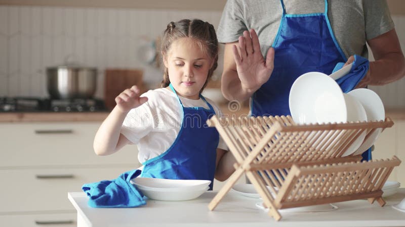 Filha e pai lavando pratos. família feliz um conceito de sonho infantil. filha criança em um avental junto com o pai