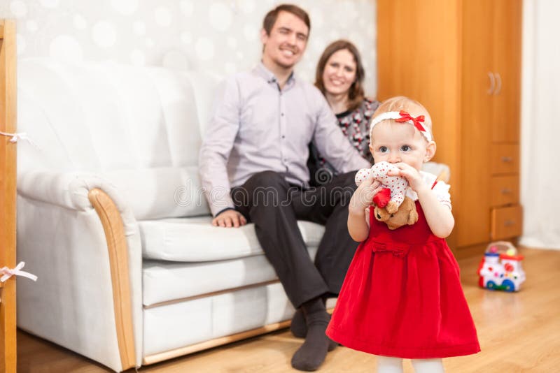 Filha pequena com assento no pai e na mãe do sofá foto de stock Filha pequena com assento no pai e na mãe do sofá foto de stock