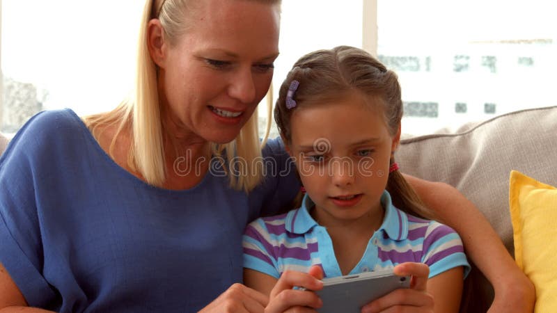 Filha que joga o jogo no telefone com mãe vídeos de arquivo