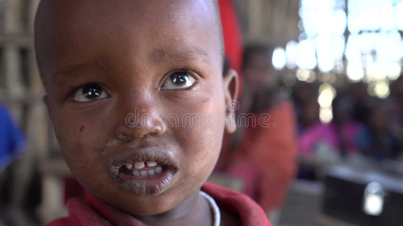 Filho da áfrica da tribo maasai a rasgar os olhos na pequena escola