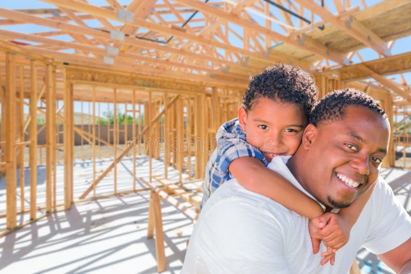 Young African American Father and Mixed Race Son On Site Inside Their New Home Construction Framing. Young African American Father and Mixed Race Son On Site Inside Their New Home Construction Framing.