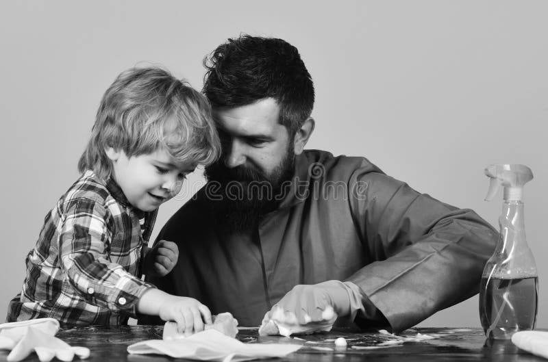 Filho e pai com as caras de sorriso perto dos pulverizadores e das luvas imagem de stock Filho e pai com as caras de sorriso perto dos pulverizadores e das luvas imagem de stock