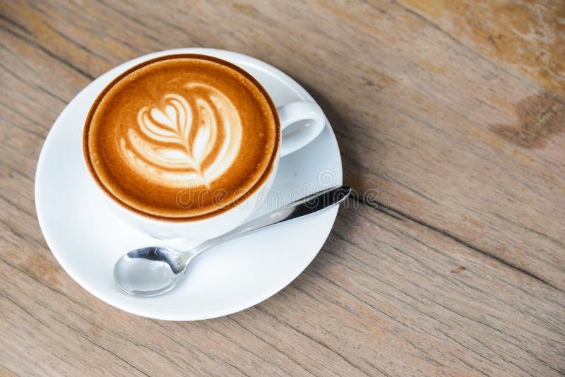 Fili?anka kawy z latte sztuk? w hearth kszta?cie w bia?ej fili?ance na drewnianym sto?owym tle fotografia stock Fili?anka kawy z latte sztuk? w hearth kszta?cie w bia?ej fili?ance na drewnianym sto?owym tle fotografia stock