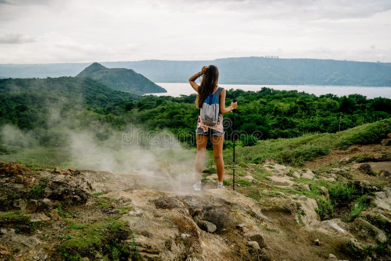 Filipina girl looking at taal volcano crater lake from trail along rim near manila in the philippines
