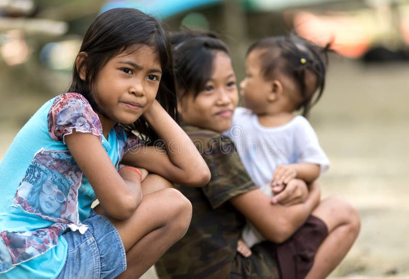 Kids of a poor filipino family are sitting outdoor, one is holding her young sister, El Nido, Philippines, on january 11, 2014. Kids of a poor filipino family are sitting outdoor, one is holding her young sister, El Nido, Philippines, on january 11, 2014