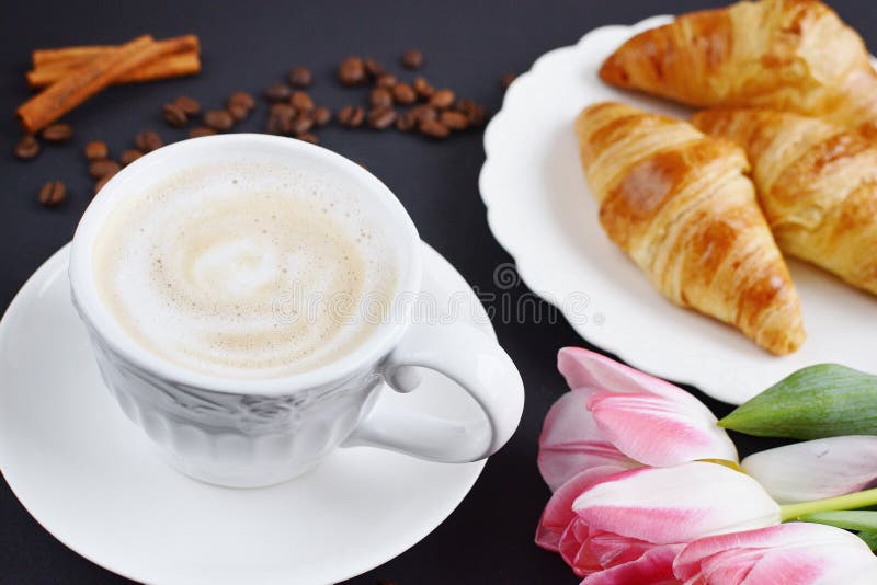 Filiżanka cappuccino i croissants z różowymi tulipanami na stole obrazy stock Filiżanka cappuccino i croissants z różowymi tulipanami na stole obrazy stock
