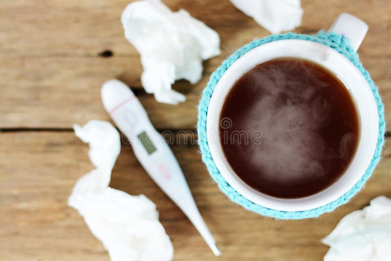 Filiżanka gorąca herbata, papierów wytarcia i termometr na drewnianego stołowego proponowania grypowym sezonie