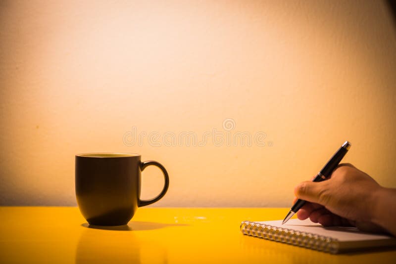 filiżanki i ręki writing na stole z lampą przy nighttime, v fotografia royalty free filiżanki i ręki writing na stole z lampą przy nighttime, v fotografia royalty free