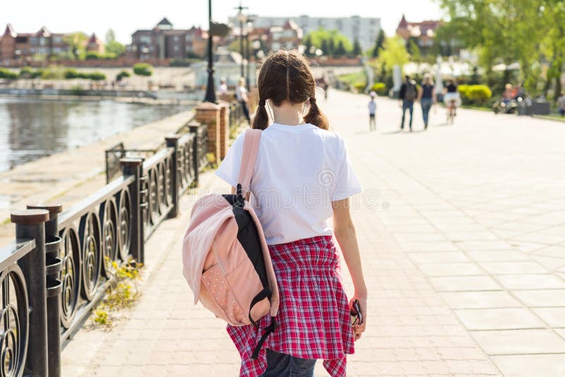 Fille adolescente d'étudiant descendant la rue avec le sac à dos De nouveau à l'école, vue arrière photos stock Fille adolescente d'étudiant descendant la rue avec le sac à dos De nouveau à l'école, vue arrière photos stock