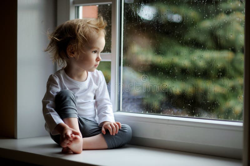 Fille adorable d'enfant en bas âge regardant cependant la fenêtre images libres de droits Fille adorable d'enfant en bas âge regardant cependant la fenêtre images libres de droits
