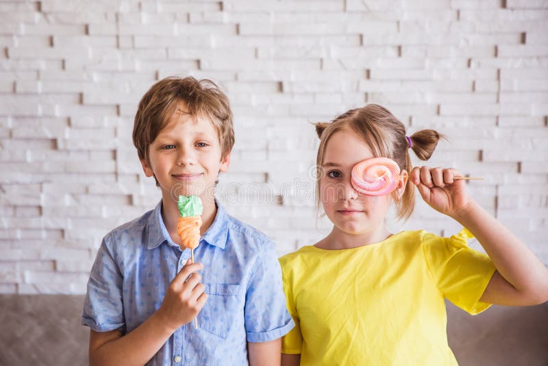 Fille adorable et gar?on tenant les meringues douces color?es sur un b?ton le jour de P?ques photos libres de droits Fille adorable et gar?on tenant les meringues douces color?es sur un b?ton le jour de P?ques photos libres de droits