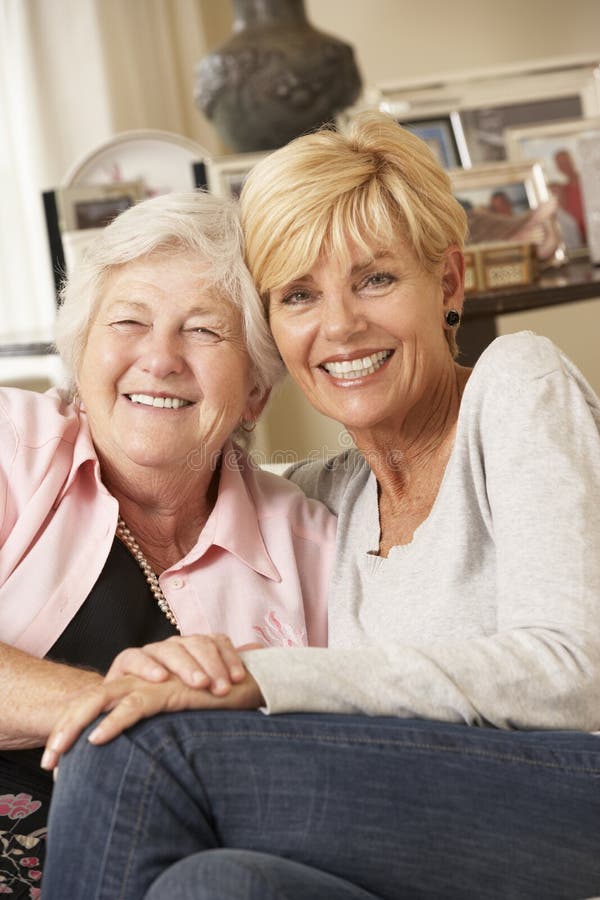 Fille adulte rendant visite à la mère supérieure s'asseyant sur Sofa At Home photographie stock libre de droits Fille adulte rendant visite à la mère supérieure s'asseyant sur Sofa At Home photographie stock libre de droits