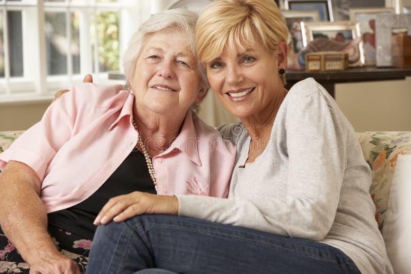 Fille adulte rendant visite à la mère supérieure s'asseyant sur Sofa At Home image stock Fille adulte rendant visite à la mère supérieure s'asseyant sur Sofa At Home image stock