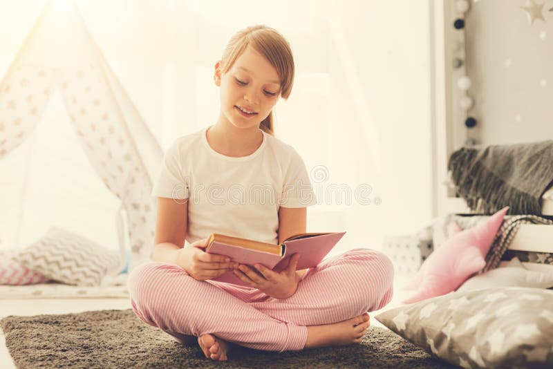Fille agréable futée lisant une histoire intéressante photos libres de droits Fille agréable futée lisant une histoire intéressante photos libres de droits