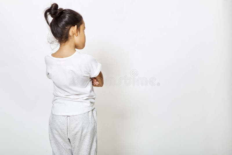 Fille arrière de vue regardant le mur. Vue arrière de petite fille regardant le mur Vue arrière sur le fond blanc, de nouveau au concept d'école