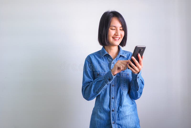 Fille asiatique avec le téléphone bleu de participation de main gauche de chemise image stock Fille asiatique avec le téléphone bleu de participation de main gauche de chemise image stock