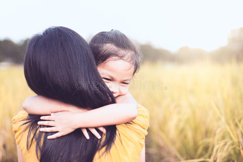 Fille asiatique heureuse de petit enfant étreignant sa mère avec amour photographie stock Fille asiatique heureuse de petit enfant étreignant sa mère avec amour photographie stock