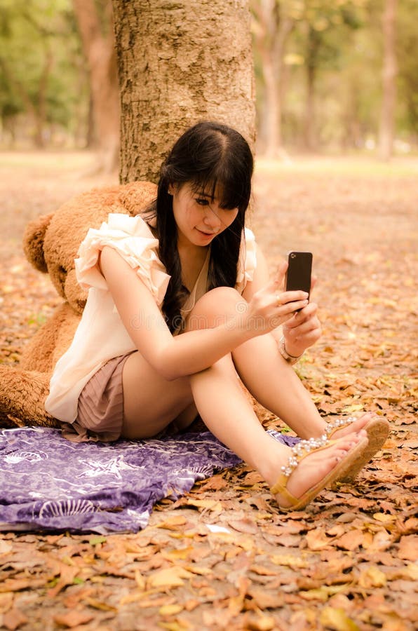 Fille asiatique jouant le téléphone portable image libre de droits Fille asiatique jouant le téléphone portable image libre de droits