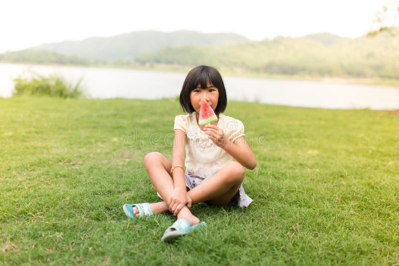 Fille asiatique mangeant la crème glacée photographie stock libre de droits Fille asiatique mangeant la crème glacée photographie stock libre de droits