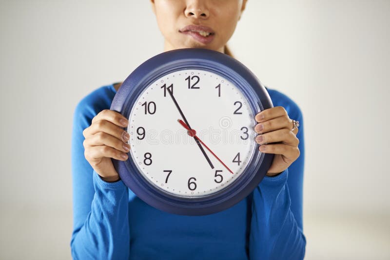 Fille asiatique tenant la grande horloge bleue avec l'effort images stock Fille asiatique tenant la grande horloge bleue avec l'effort images stock