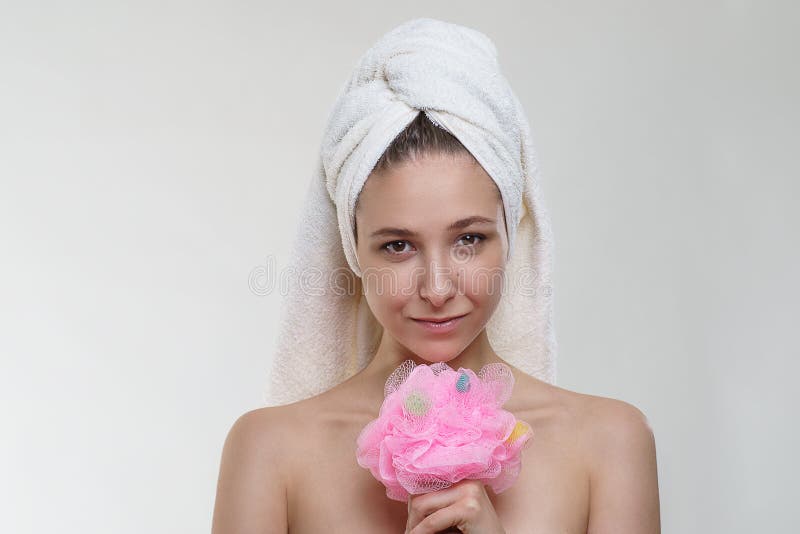 Fille assez jeune heureuse avec la belle peau fraîche et sourire merveilleux dans une serviette posant avec une éponge sur le fon images libres de droits Fille assez jeune heureuse avec la belle peau fraîche et sourire merveilleux dans une serviette posant avec une éponge sur le fon images libres de droits