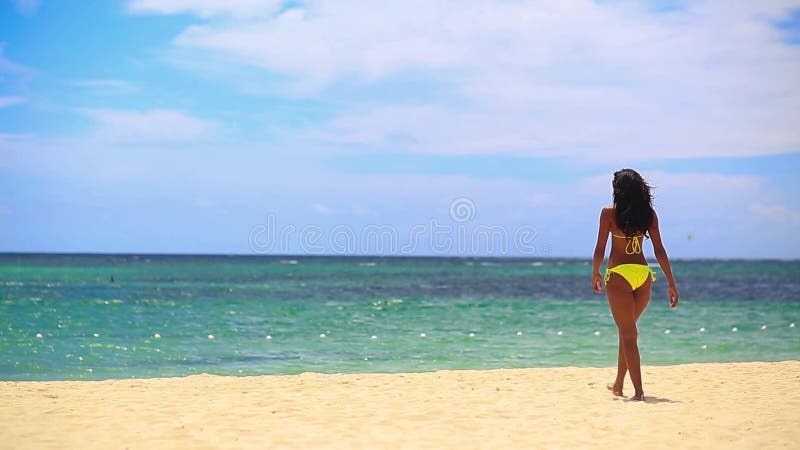 Fille assez noire dans le bikini jaune allant à la mer