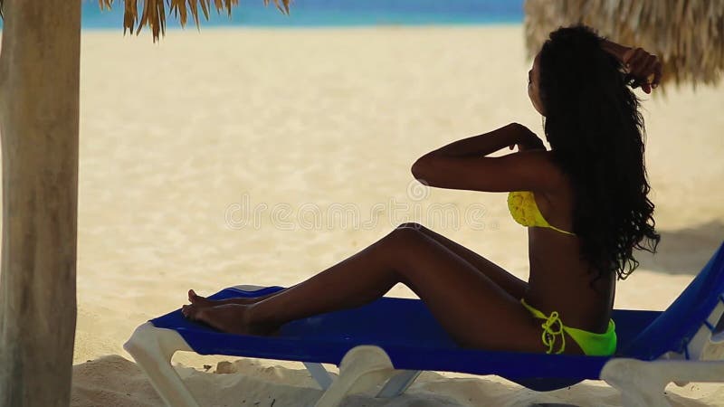 Fille assez noire dans le bikini jaune se reposant sur la plage