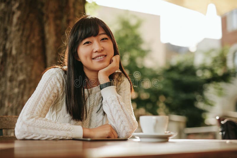 Fille attirante s'asseyant au café extérieur et au sourire photo stock Fille attirante s'asseyant au café extérieur et au sourire photo stock