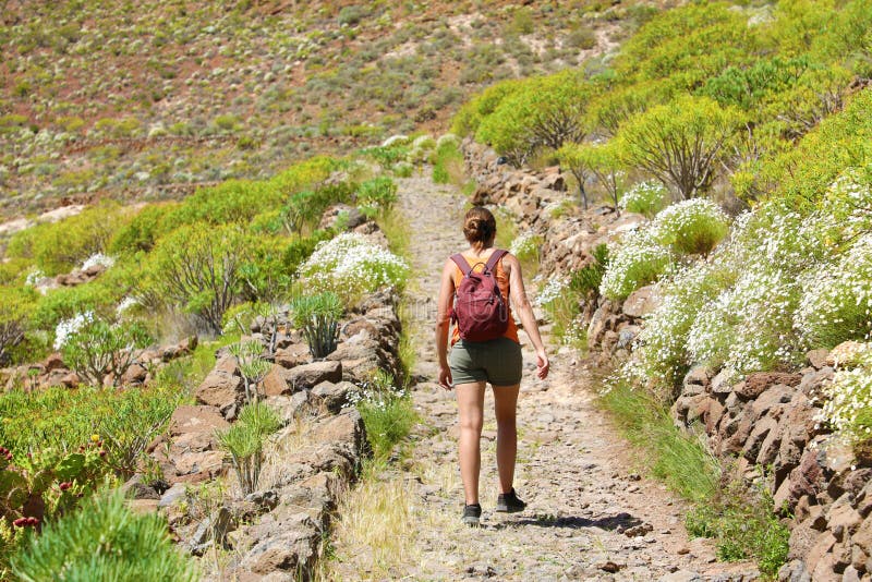 Fille avec des promenades de sac à dos le long du chemin de montagne Une femme marche le long d'une route pierreuse dans Ténérife photographie stock libre de droits Fille avec des promenades de sac à dos le long du chemin de montagne Une femme marche le long d'une route pierreuse dans Ténérife photographie stock libre de droits