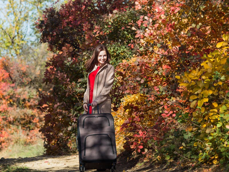 Fille avec le bagage sur la route de campagne dans la forêt photo stock Fille avec le bagage sur la route de campagne dans la forêt photo stock