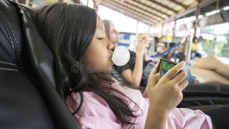 Fille avec le bubble-gum jouant le jeu au téléphone photos libres de droits Fille avec le bubble-gum jouant le jeu au téléphone photos libres de droits