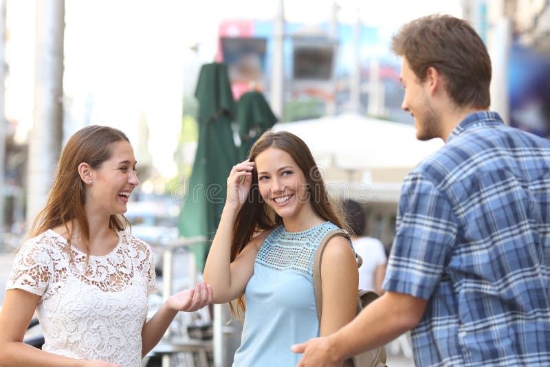 Candid girl with a friend flirting with a boy in the street. Candid girl with a friend flirting with a boy in the street