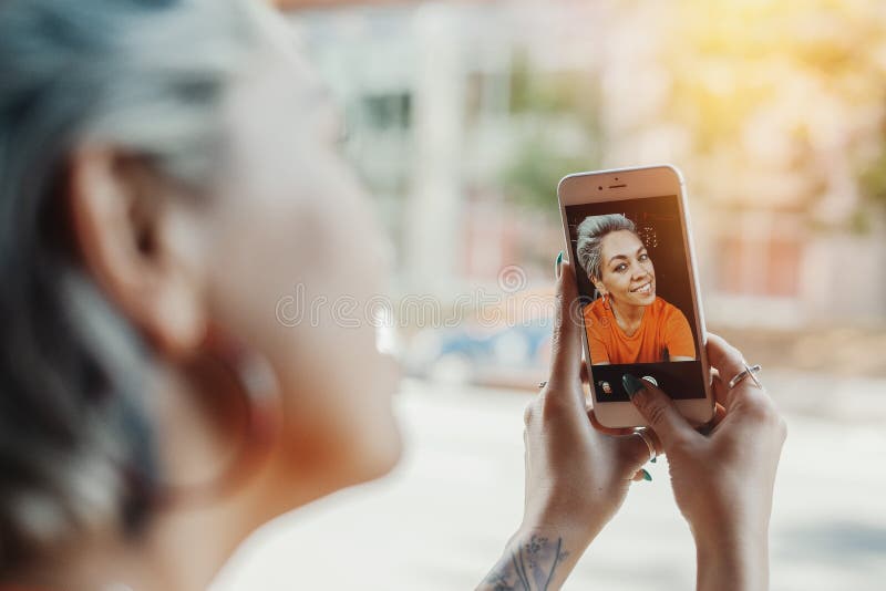Fille blonde attirante dans le T-shirt orange faisant le selfie au café par son téléphone photos stock Fille blonde attirante dans le T-shirt orange faisant le selfie au café par son téléphone photos stock