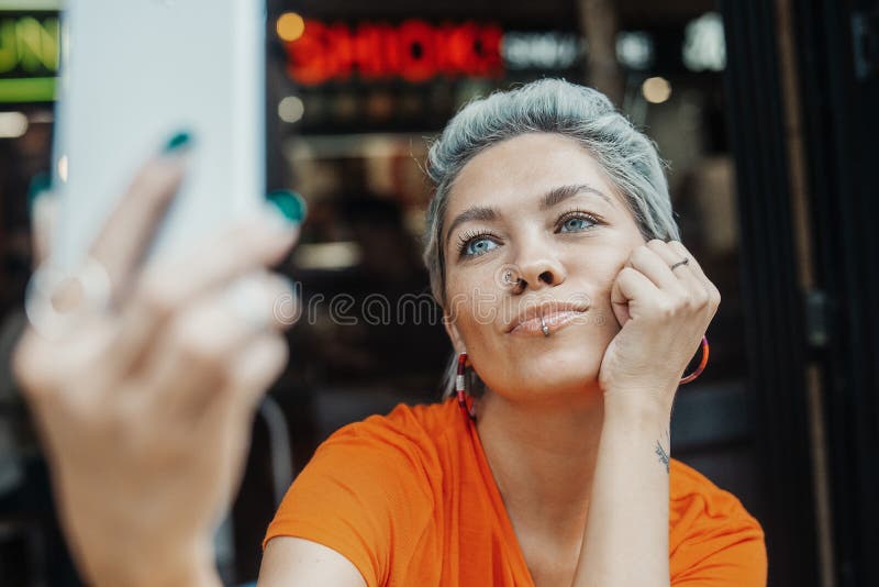 Fille blonde attirante faisant le selfie au café et buvant du café image stock Fille blonde attirante faisant le selfie au café et buvant du café image stock