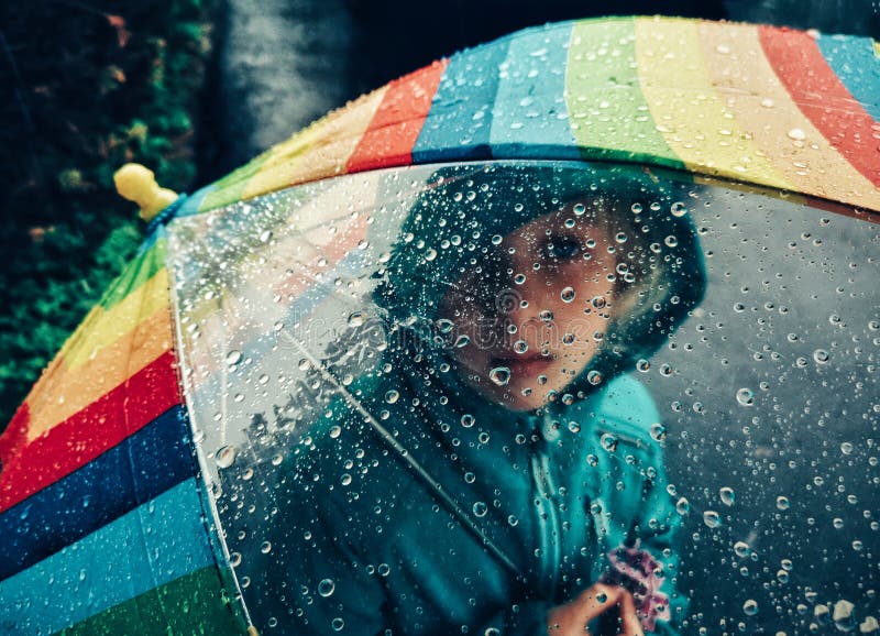 Fille caucasienne regardant par le parapluie d'arc-en-ciel avec de grandes baisses de pluie photos libres de droits Fille caucasienne regardant par le parapluie d'arc-en-ciel avec de grandes baisses de pluie photos libres de droits